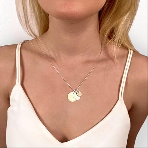 Kvinna med silverhalsband med graverade runda namnbrickor i olika storlekar i äkta silver med barnens namn på vardera brickan