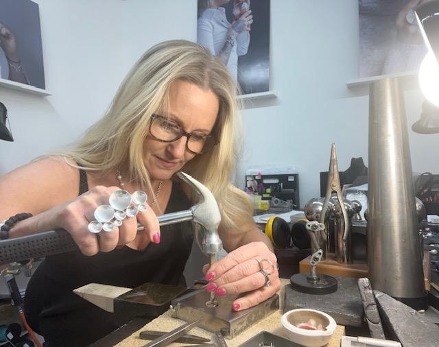amanda egilson i smyckesateljén när hon jobbar och hamrar in namn på en namnbricka