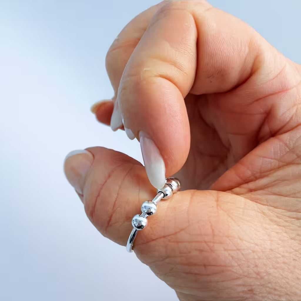 Fingrar som pillar på kulorna på en stressring i äkta silver för att dämpa ångestdämpande och få ro. Lugnande.