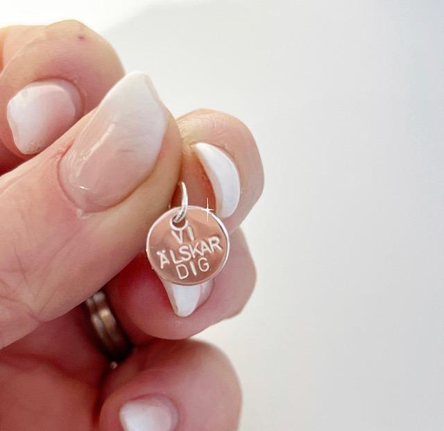 Rund liten namnbricka med texten Vi älskar dig i äkta silver